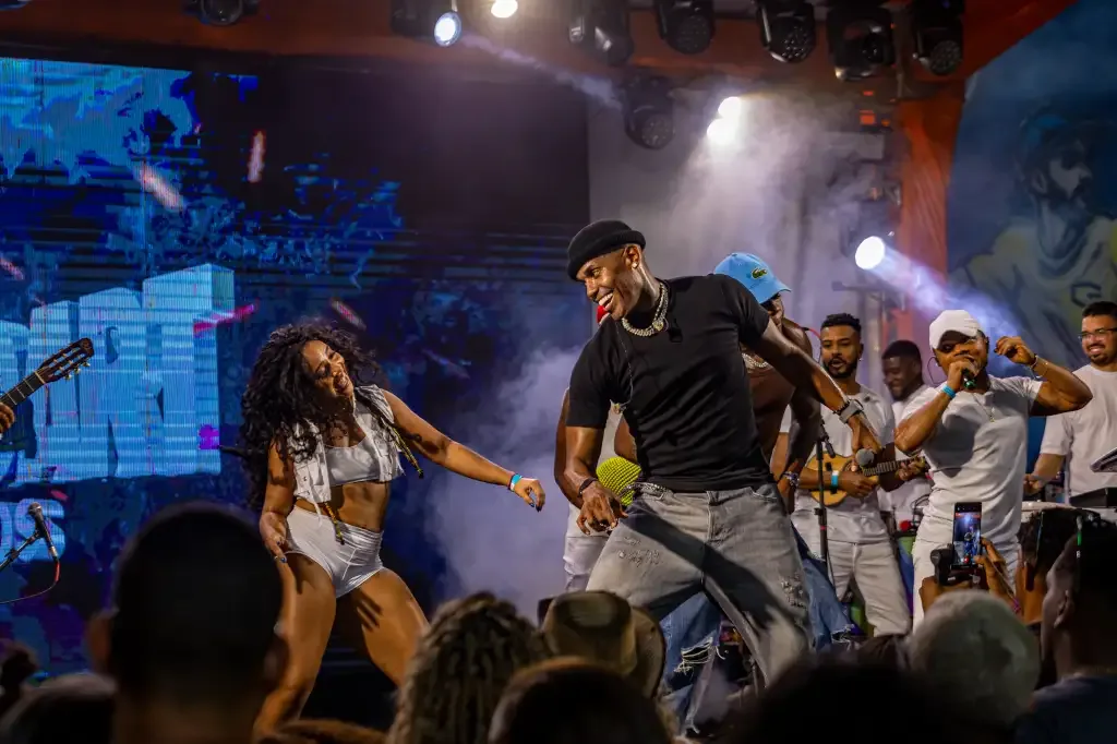Homem e mulher dançando no palco e uma banda tocando atrás