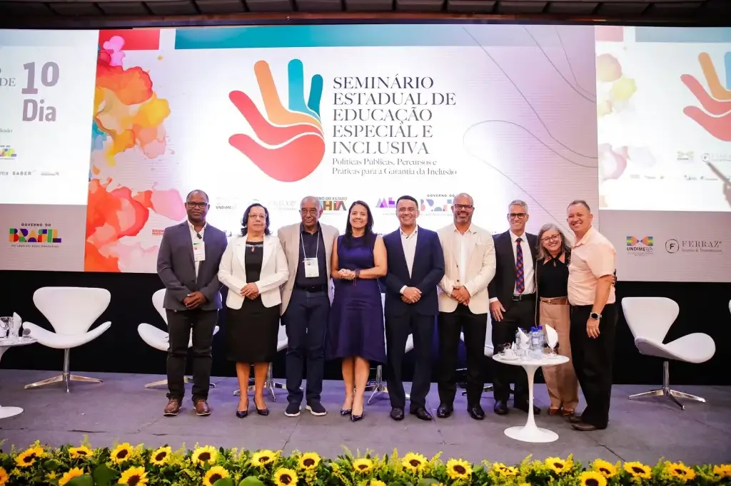 Homens e mulheres em um palco enfileirados pousando para foto