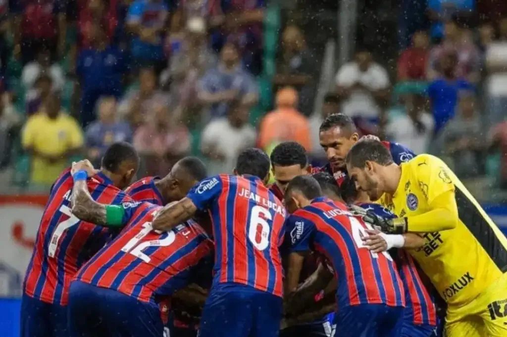 Time do esporte clube bahia em circulo de costas com uma mão em cima da outra.