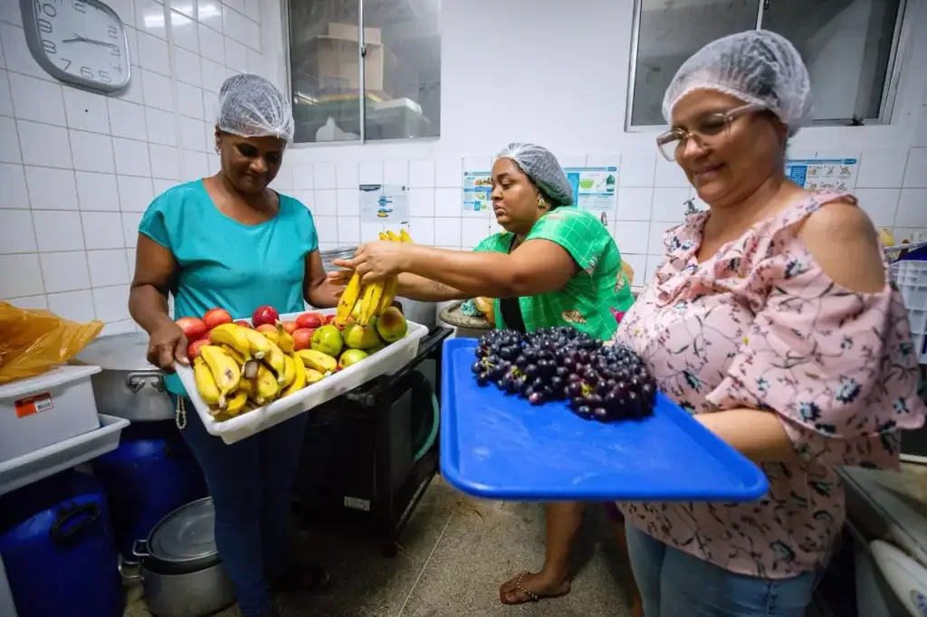 Três mulheres segurando bandeja com frutas