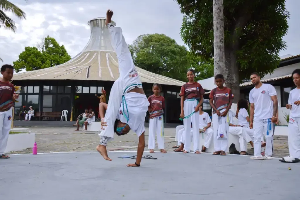 Roda de capoeira com jovem no meio de cabeça para baixo