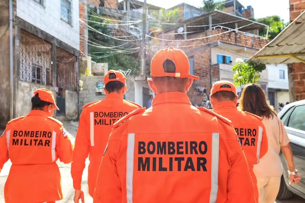 Bombeiros com roupa na cor laranja andando pela rua