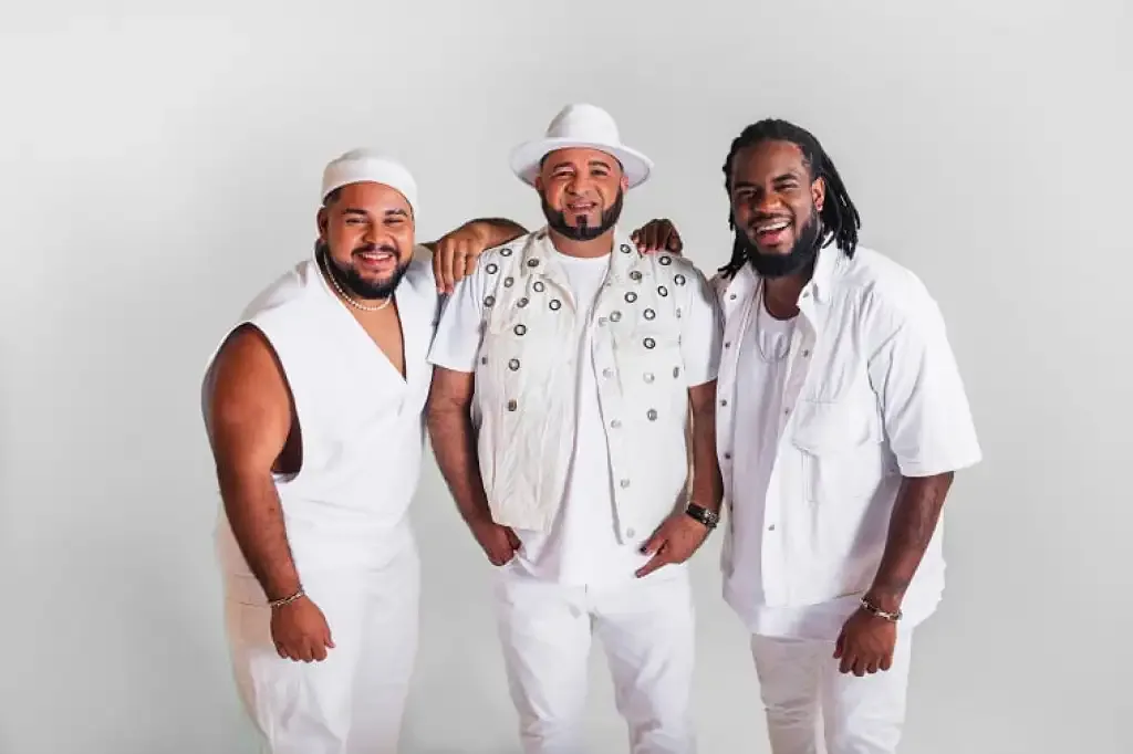 Três homens vestidos de branco pousando para foto