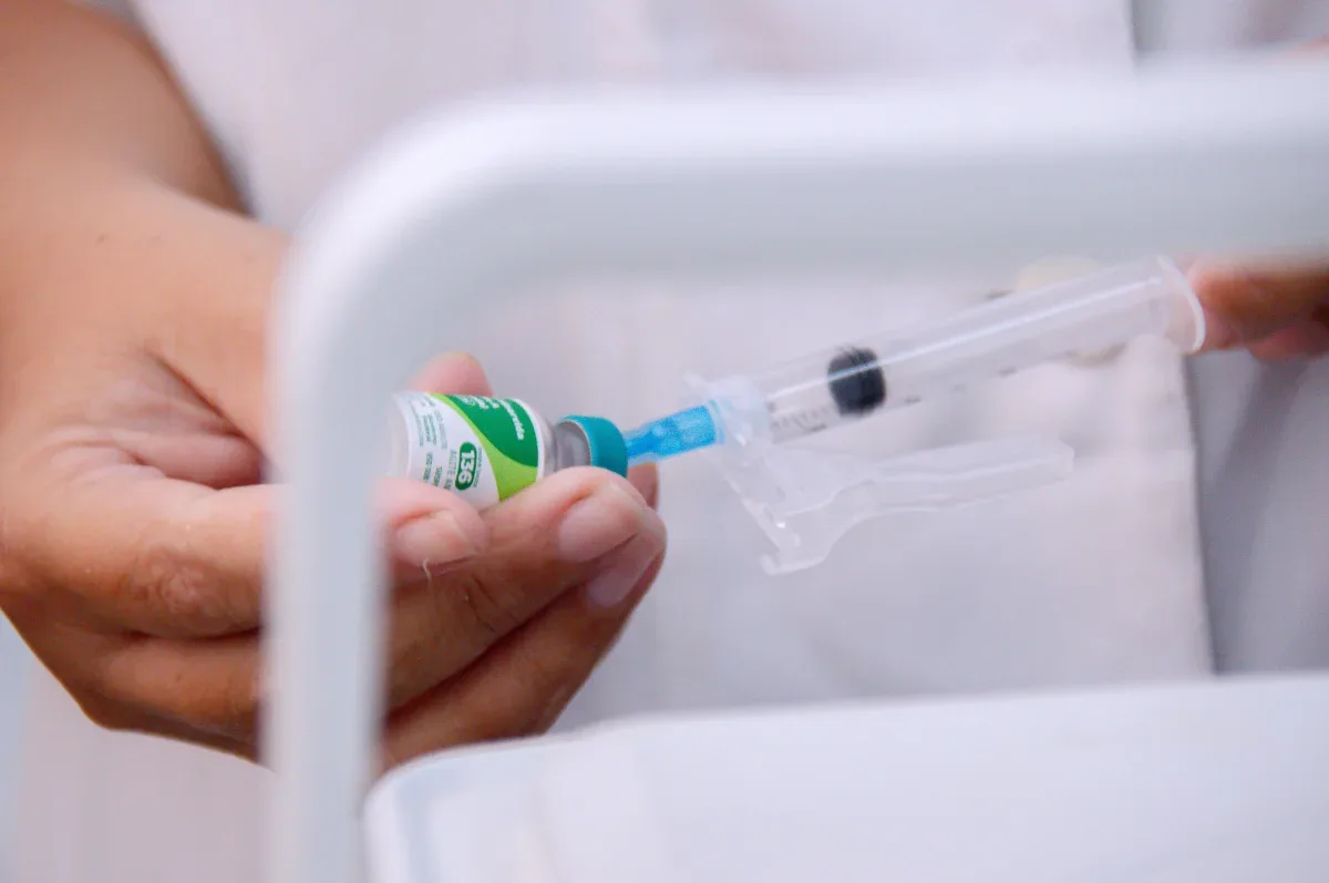 Enfermeira tirando sando seringa para tirar solução para vacina da ampola.