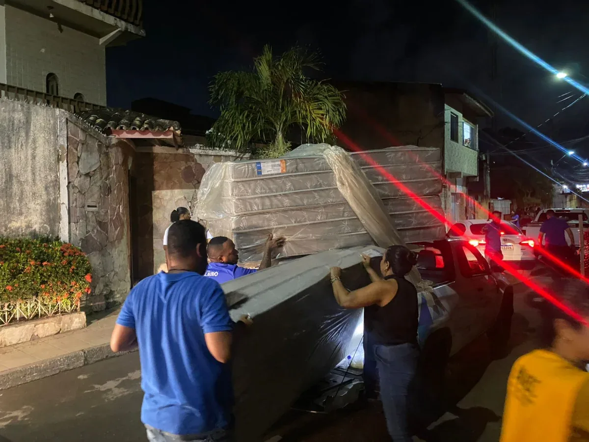 Pessoa s tirando colcões do carro para entregar a moradores o bairro Portão em Lauro de Freitas