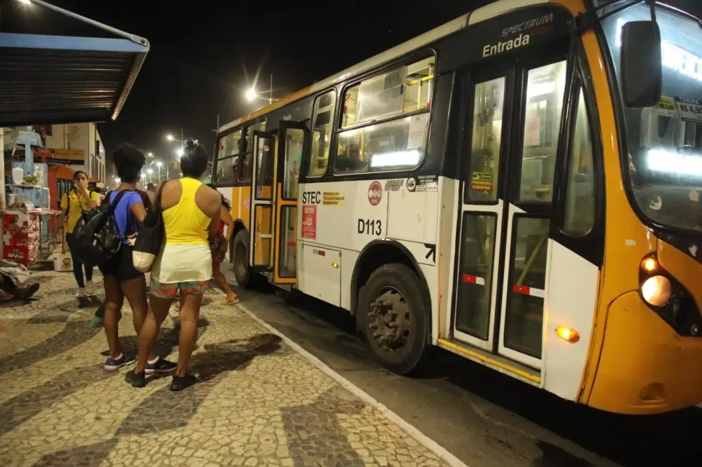 Pessoas e ônibus parado no ponto.