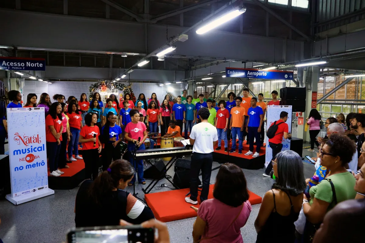 Coral Neojiba cantando na rodoviári e pessoas assistindo.