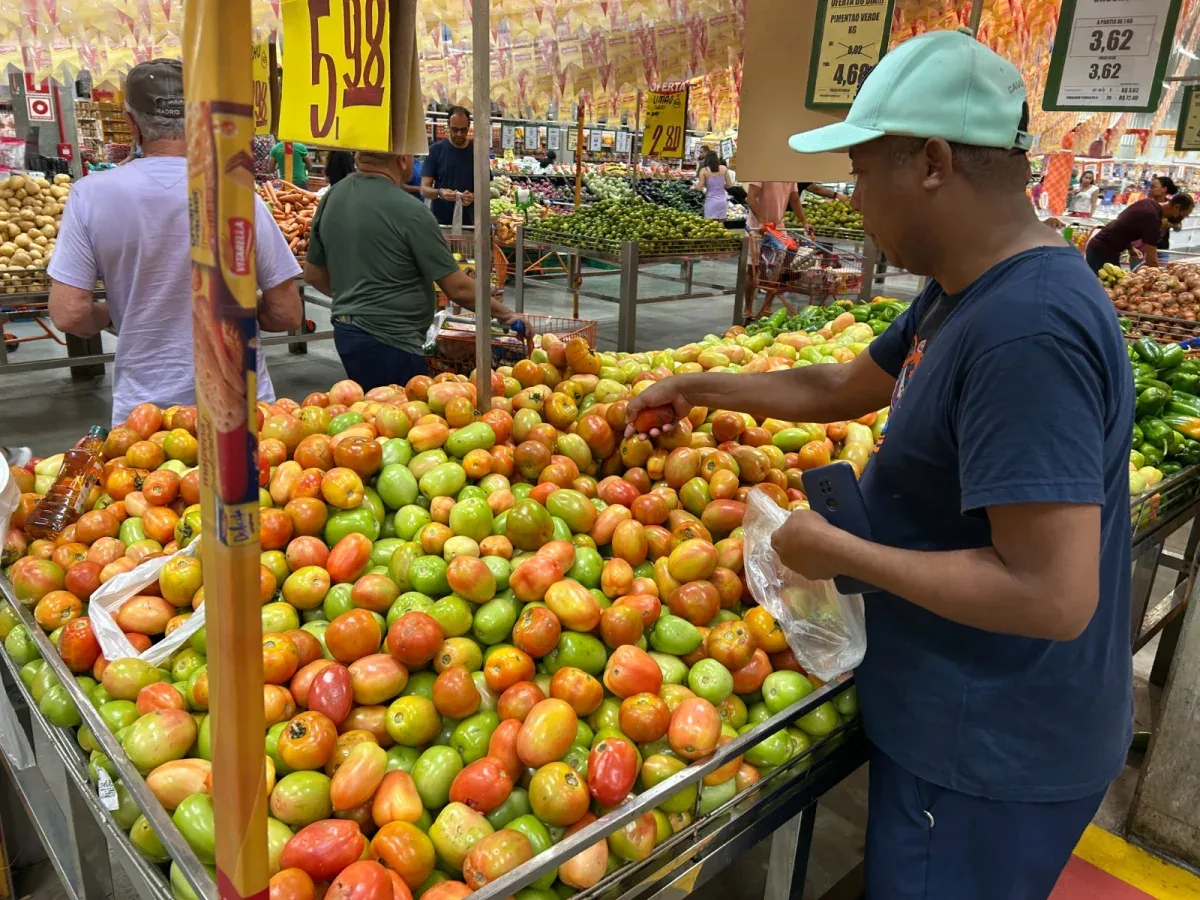 Homem escolhendo tomates no mercado