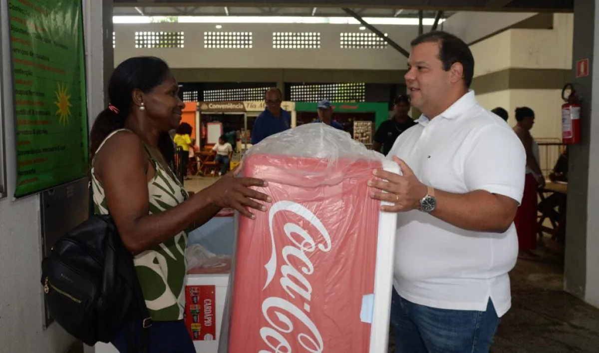 Sevidor entregando caixa térmica a uma mulher que trabalha como ambulante