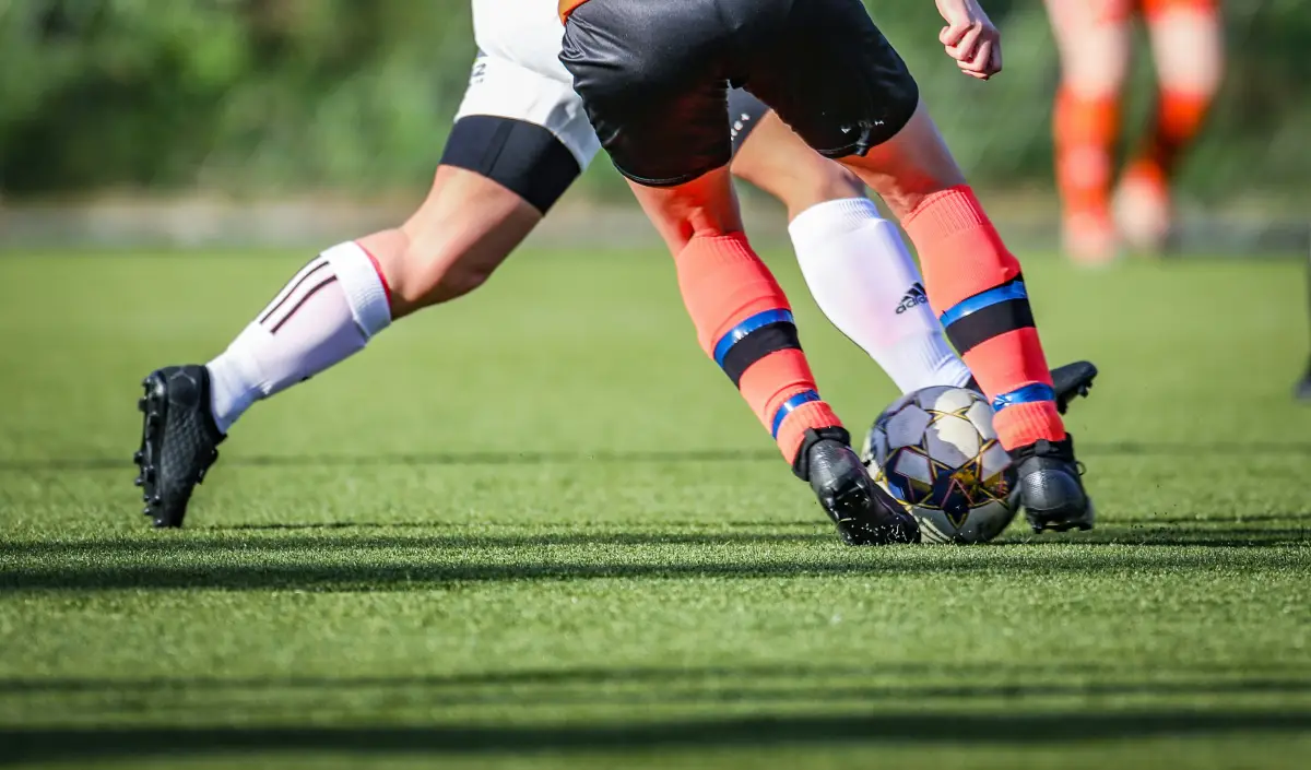 Pernas de dois jogadores de futebol jogando no campo de grama Pernas de dois jogadores de futebol jogando no campo de grama