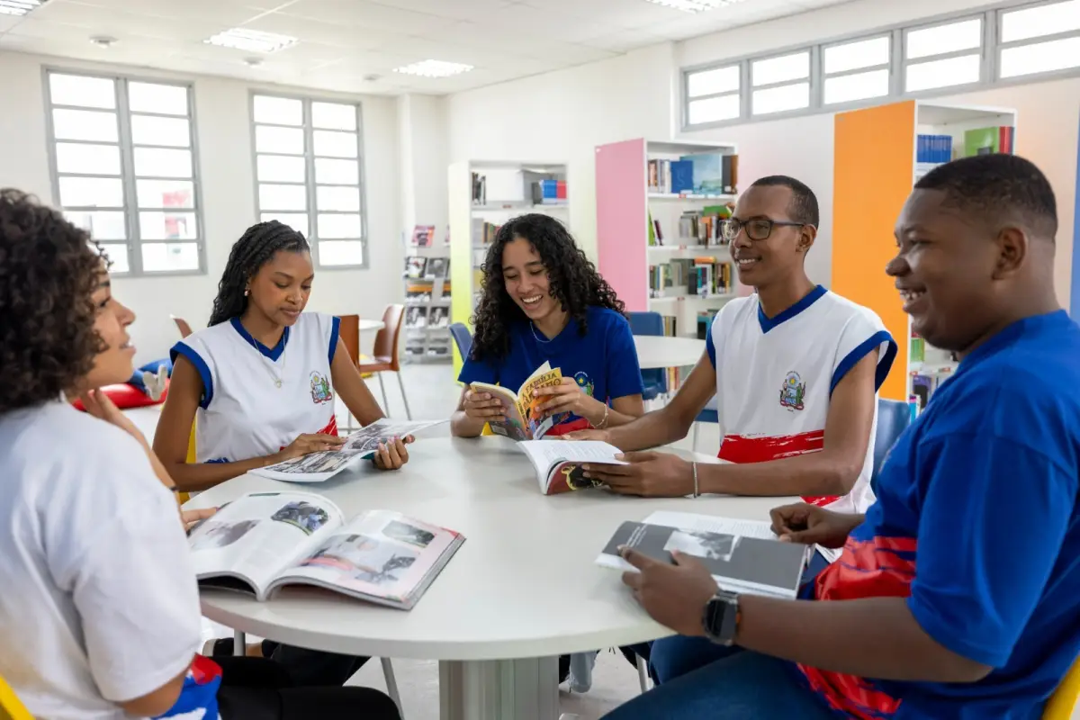 Estudantes reunidos em uma mesa lendo livros