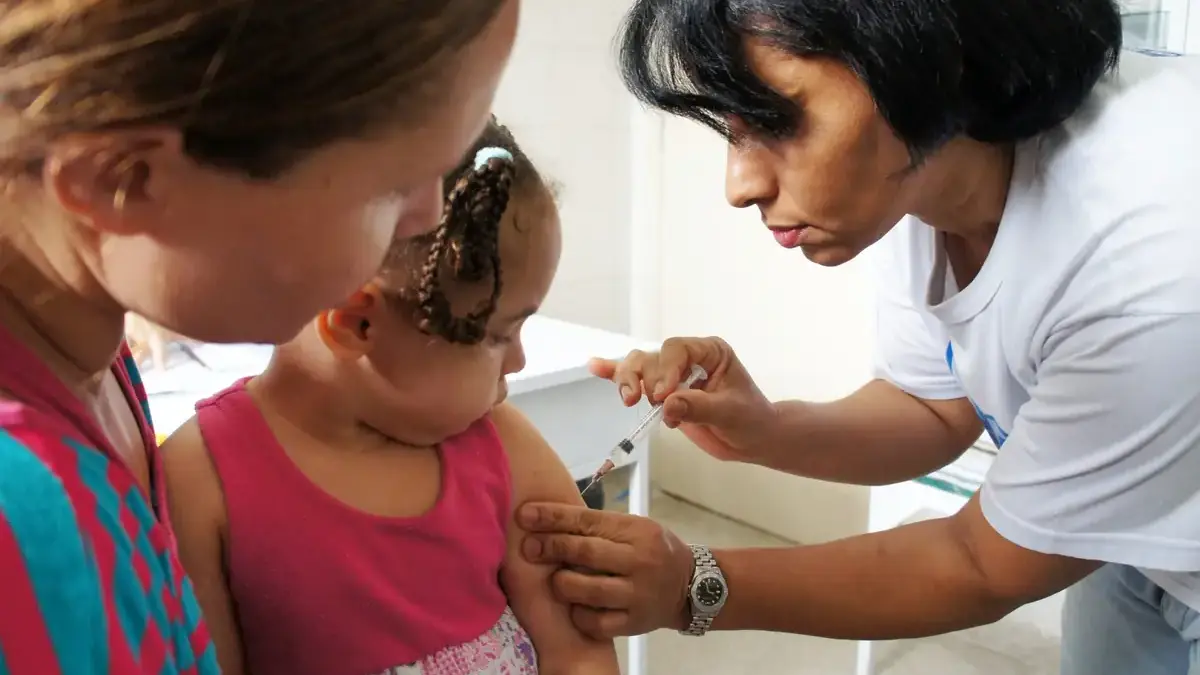 Crian&ccedil;a de colo sendo vacinada.
