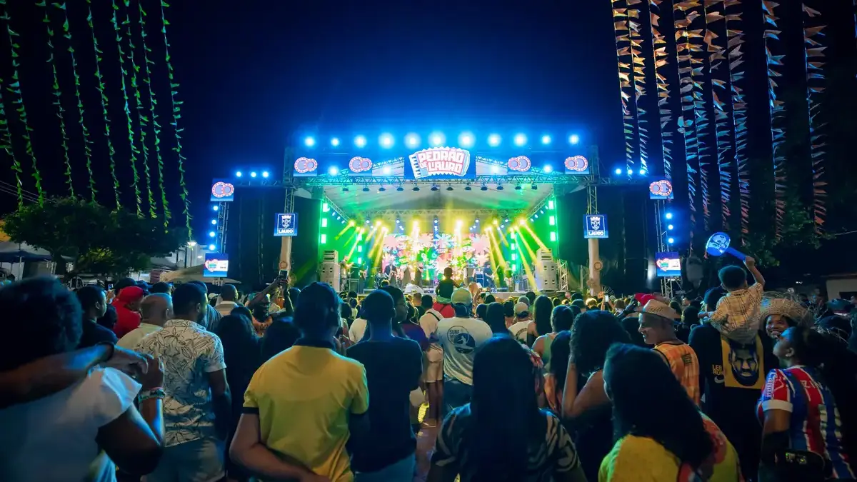Cantor Flávio José em show de forró, palco iluminado, público animado, evento cultural na Bahia