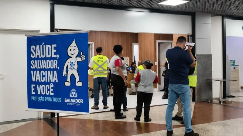 Posto de vacinação contra influenza no Aeroporto de Salvador, com pessoas recebendo a dose.